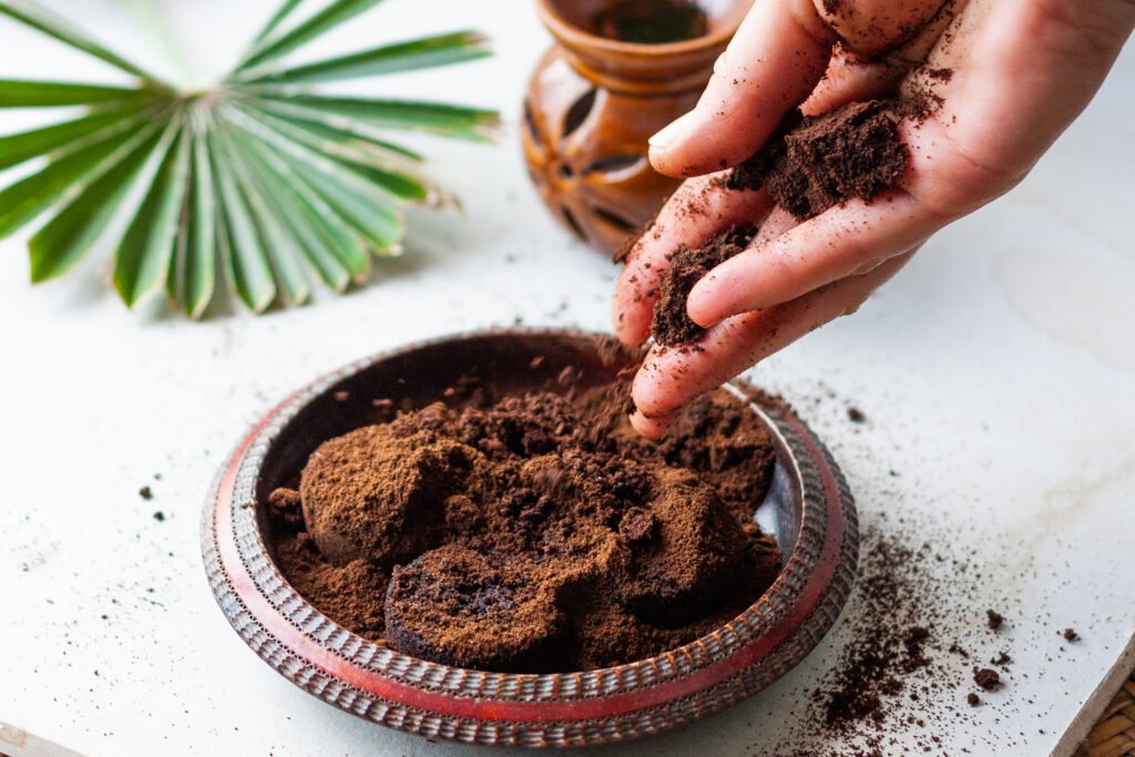 Woman's hand crumbles coffee grounds into wooden bowl