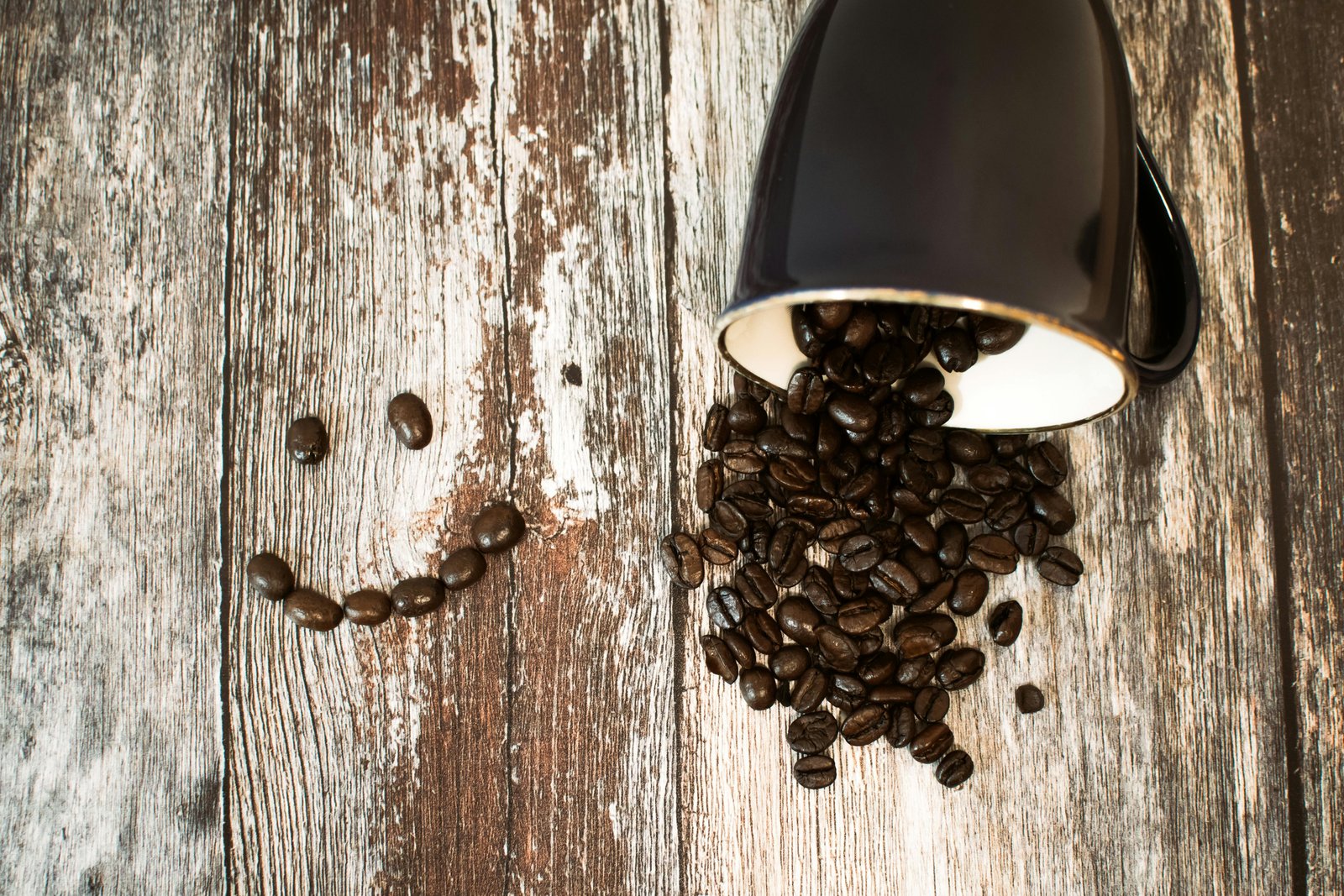 Coffee beans pouring from a cup onto the table- Do Coffee Beans Go Bad? Shelf Life Tips